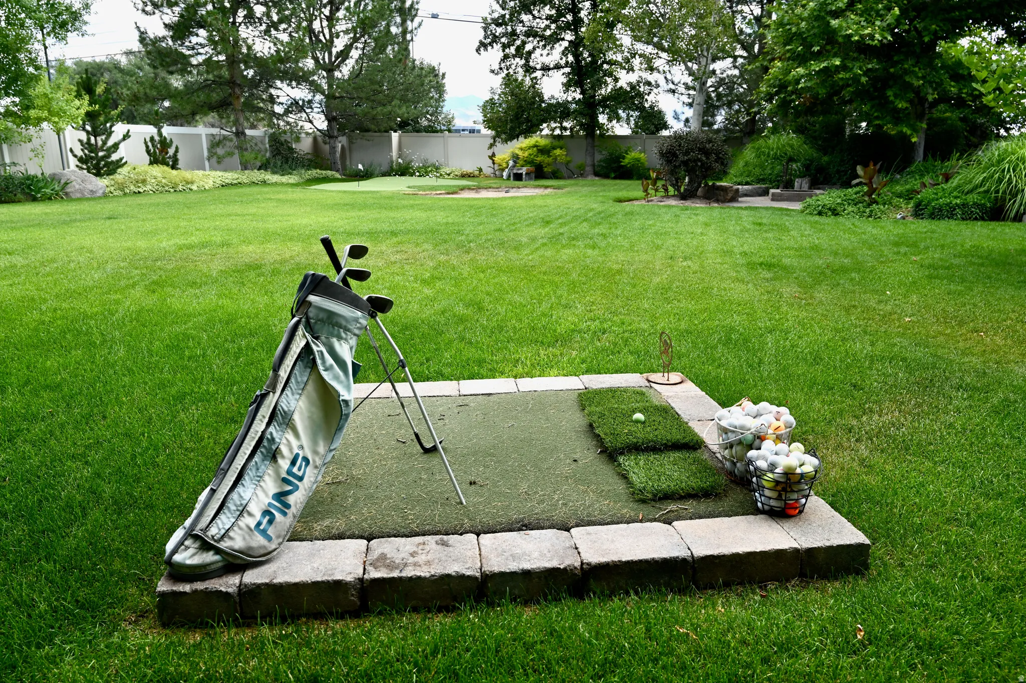 Spacious backyard featuring a putting green, sand trap, and a dedicated golf practice area with a block border