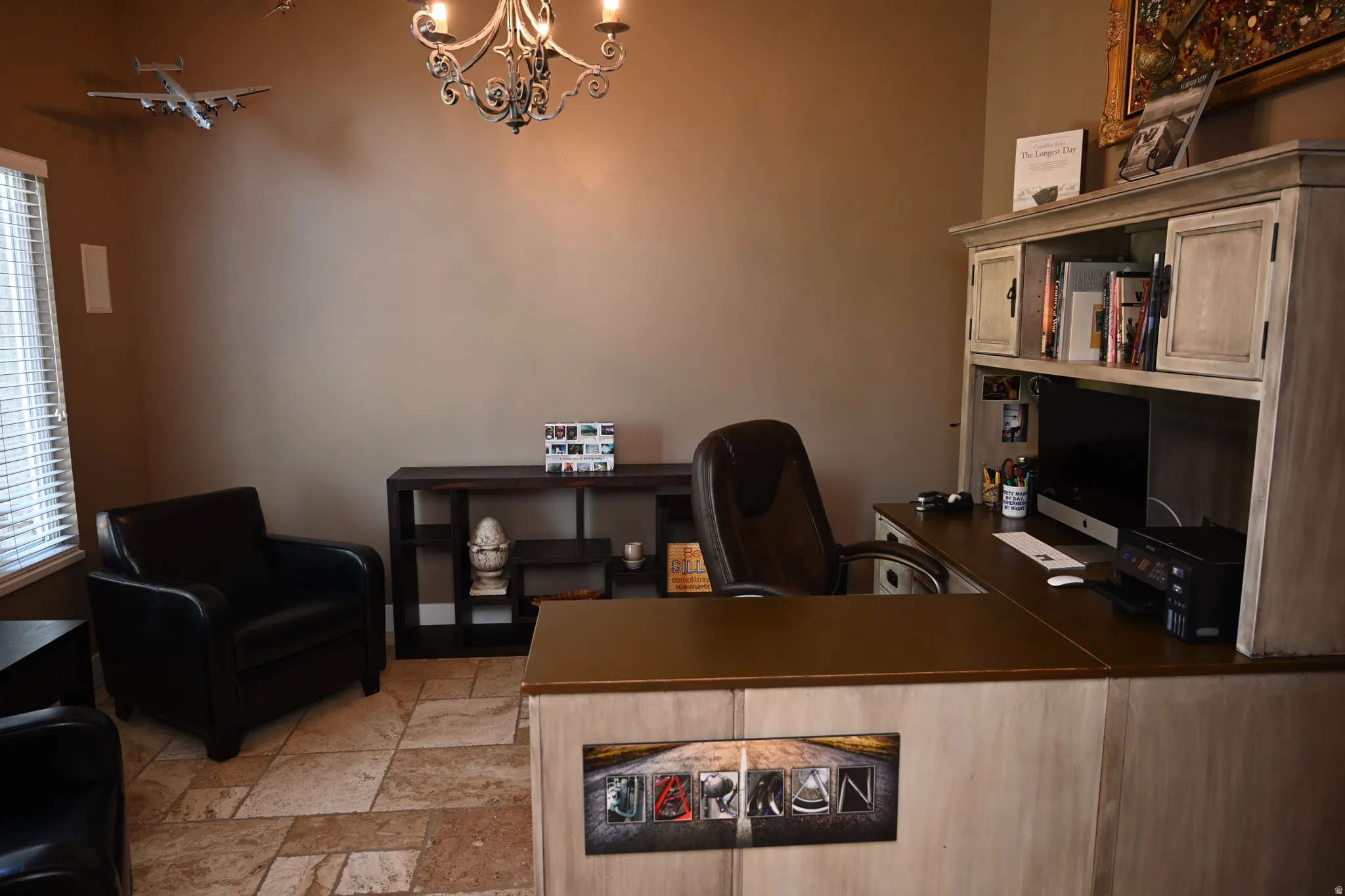 Dedicated office space featuring expansive built-in desk cabinetry, a decorative chandelier, and tile flooring