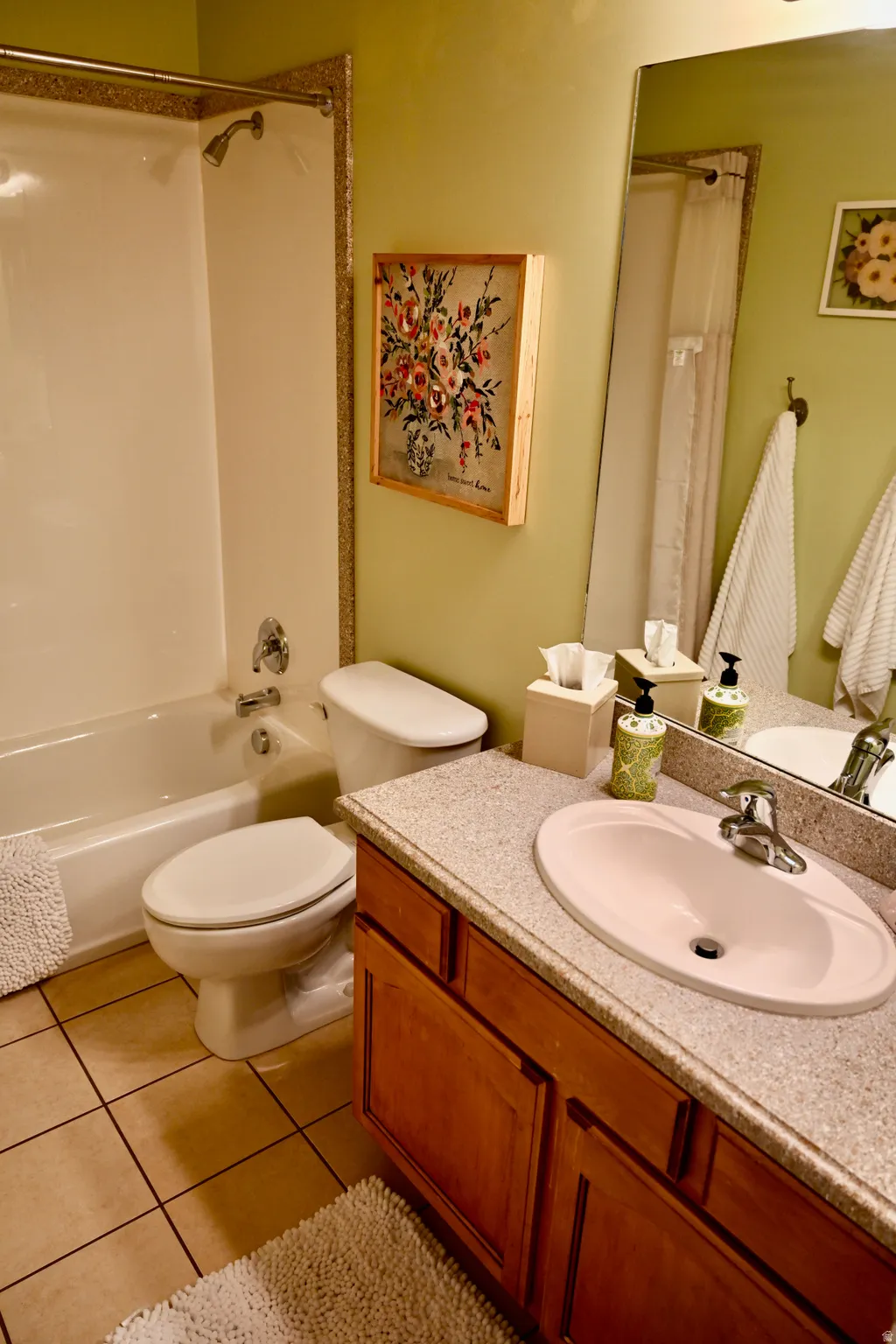 Bathroom featuring a single vanity with wood-finish cabinetry, a light-colored countertop, and an integrated oval sink