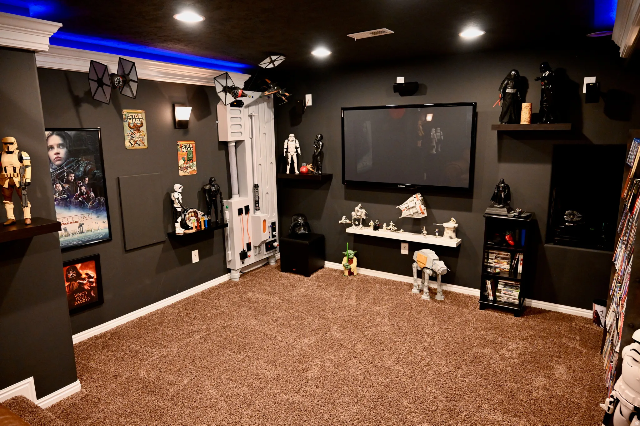 Spacious media room featuring plush carpeting, recessed lighting, wall-mounted television, built-in shelving, and accent wall sconces