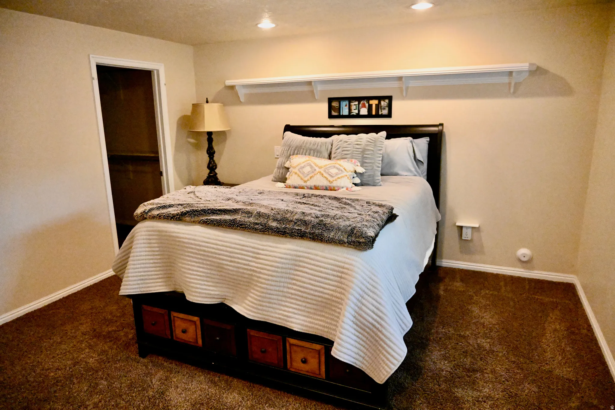 Carpeted bedroom with neutral wall tones and white baseboards