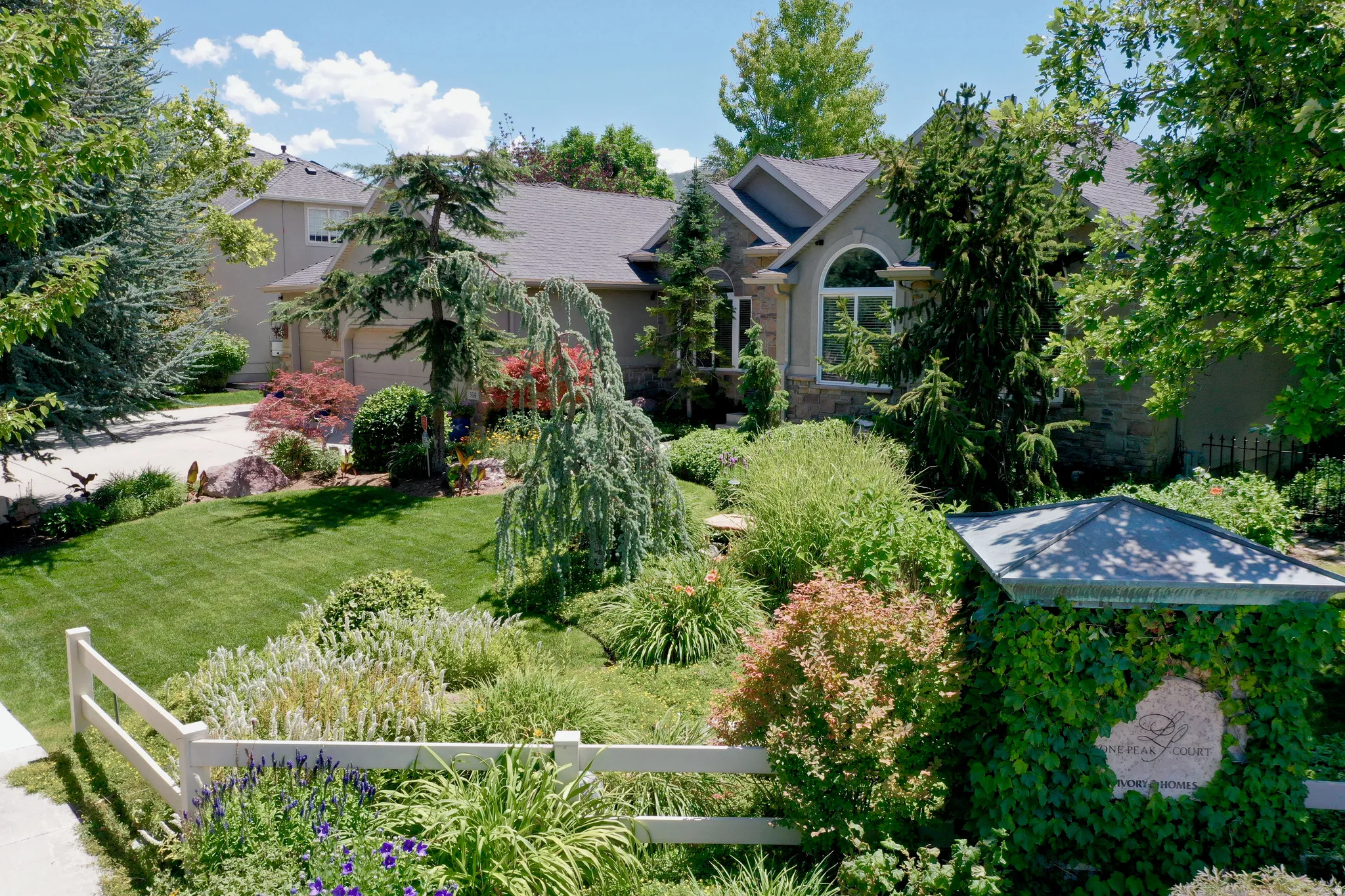 Stucco and stone exterior home featuring an arched window, a gabled roofline, and an attached garage