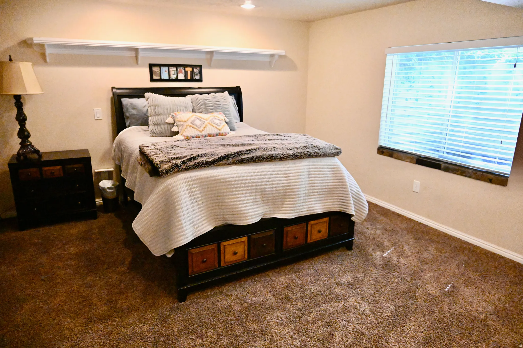 Carpeted bedroom featuring a large window with blinds and a built-in window ledge