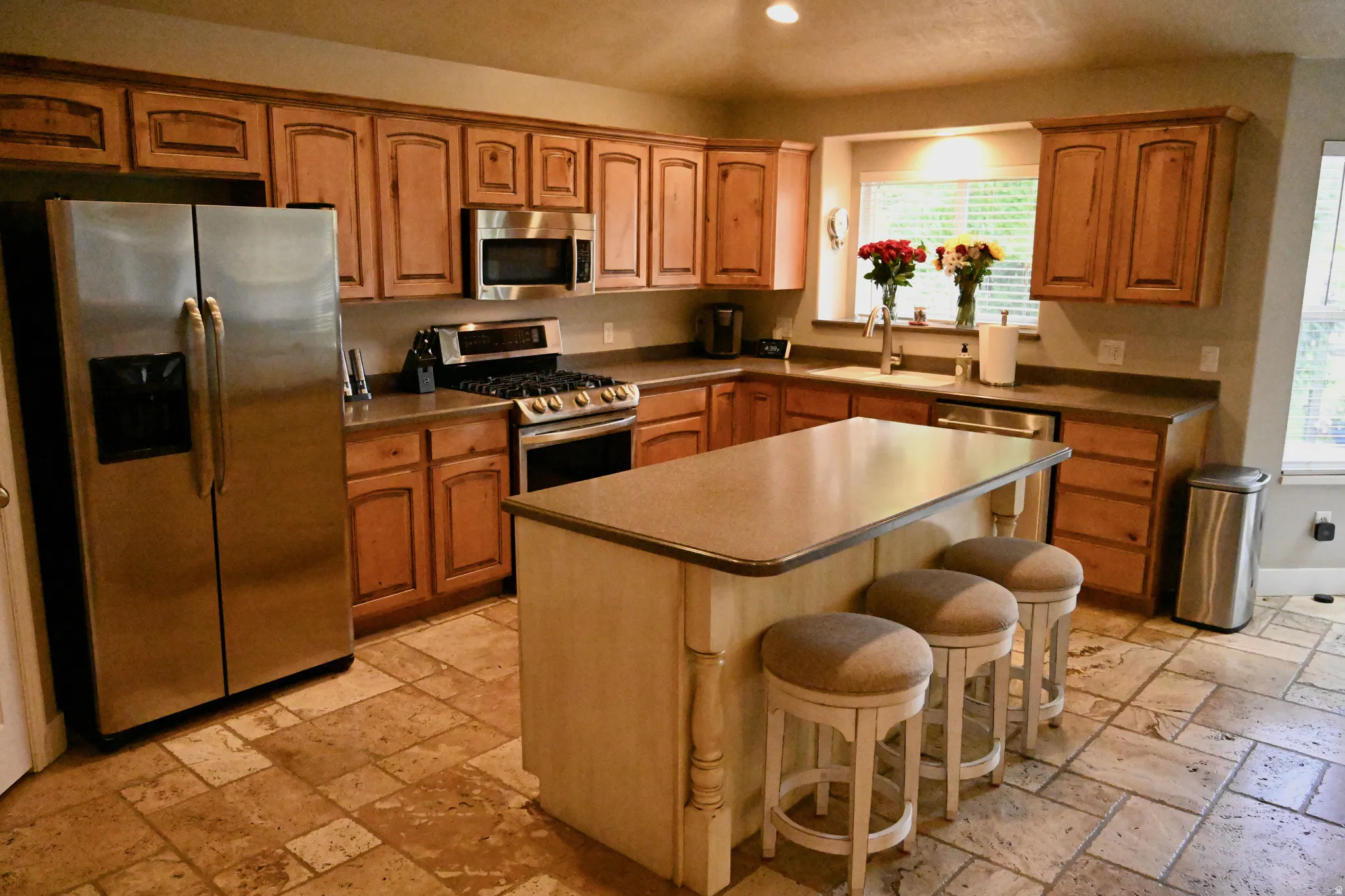 Full kitchen featuring extensive wood cabinetry, stainless steel appliances, a center island, and tiled flooring