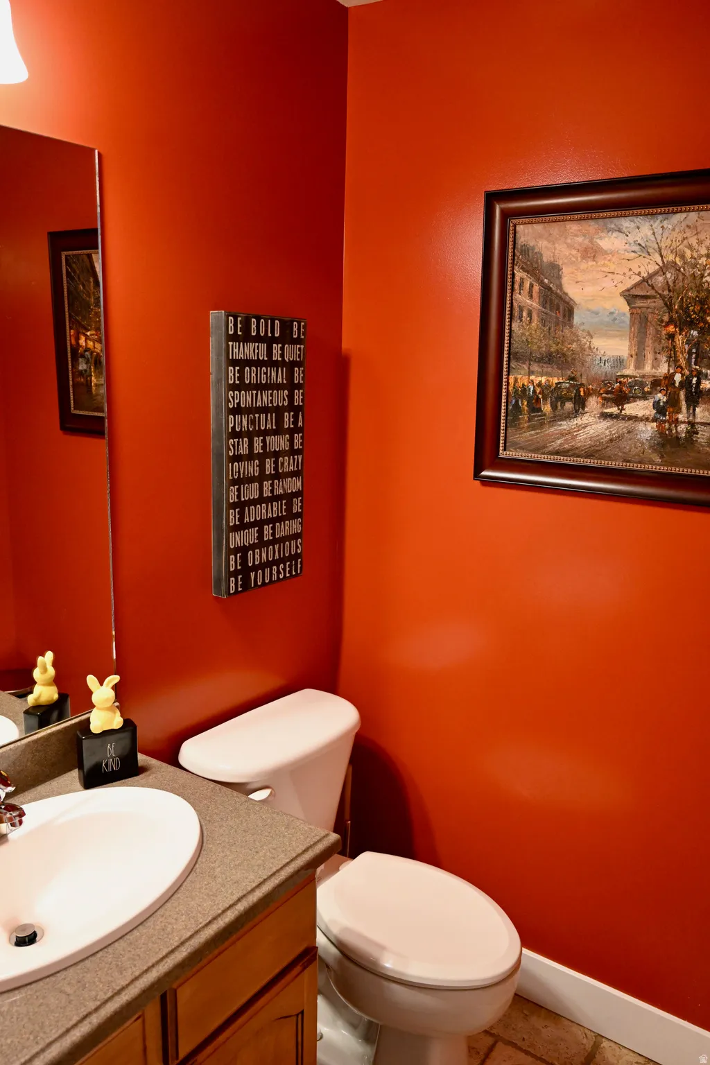 Powder room featuring a single-sink vanity with wood cabinetry, a light-colored countertop, and an oval undermount sink