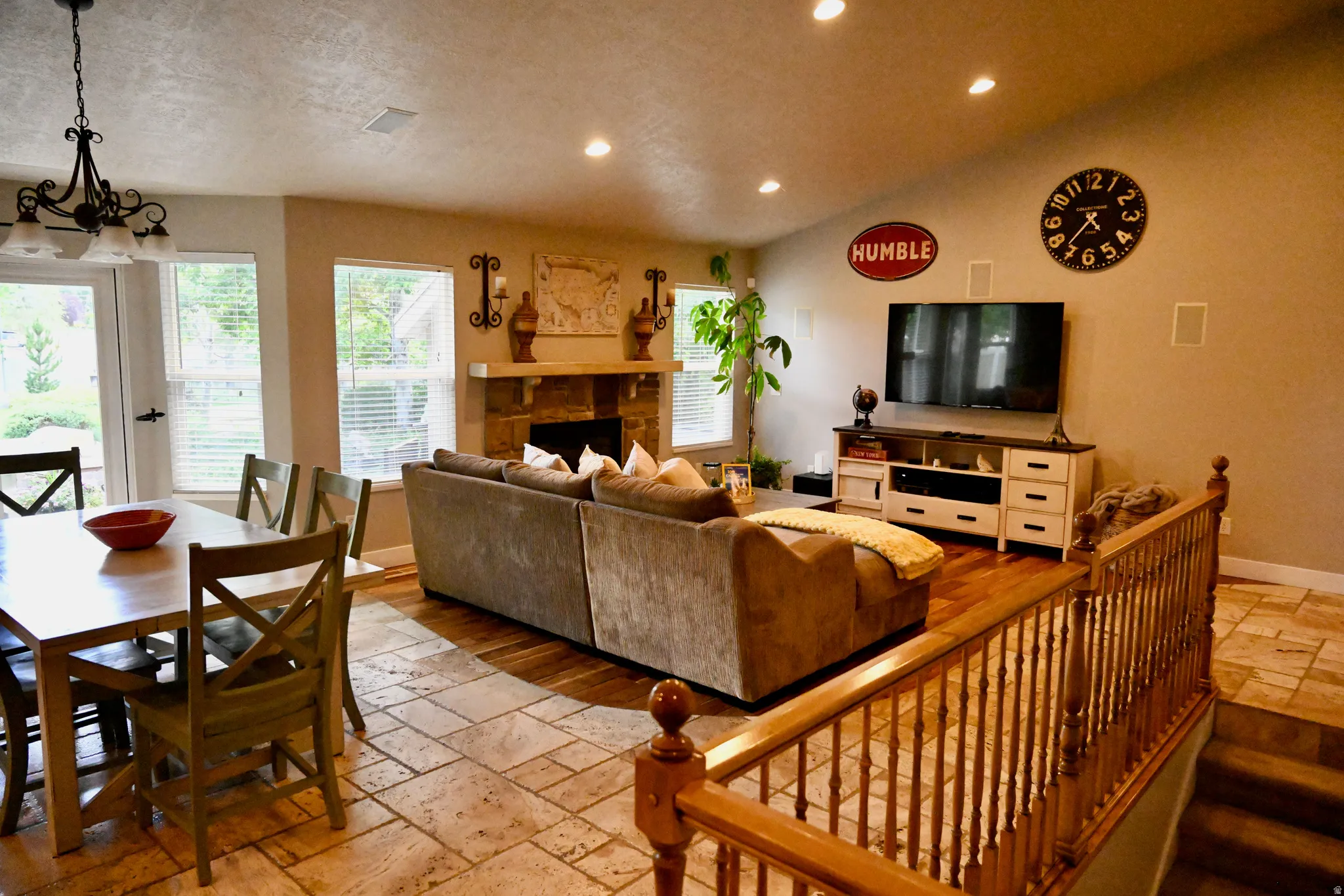 Open-concept living space with a stone-clad fireplace and wood-finish flooring