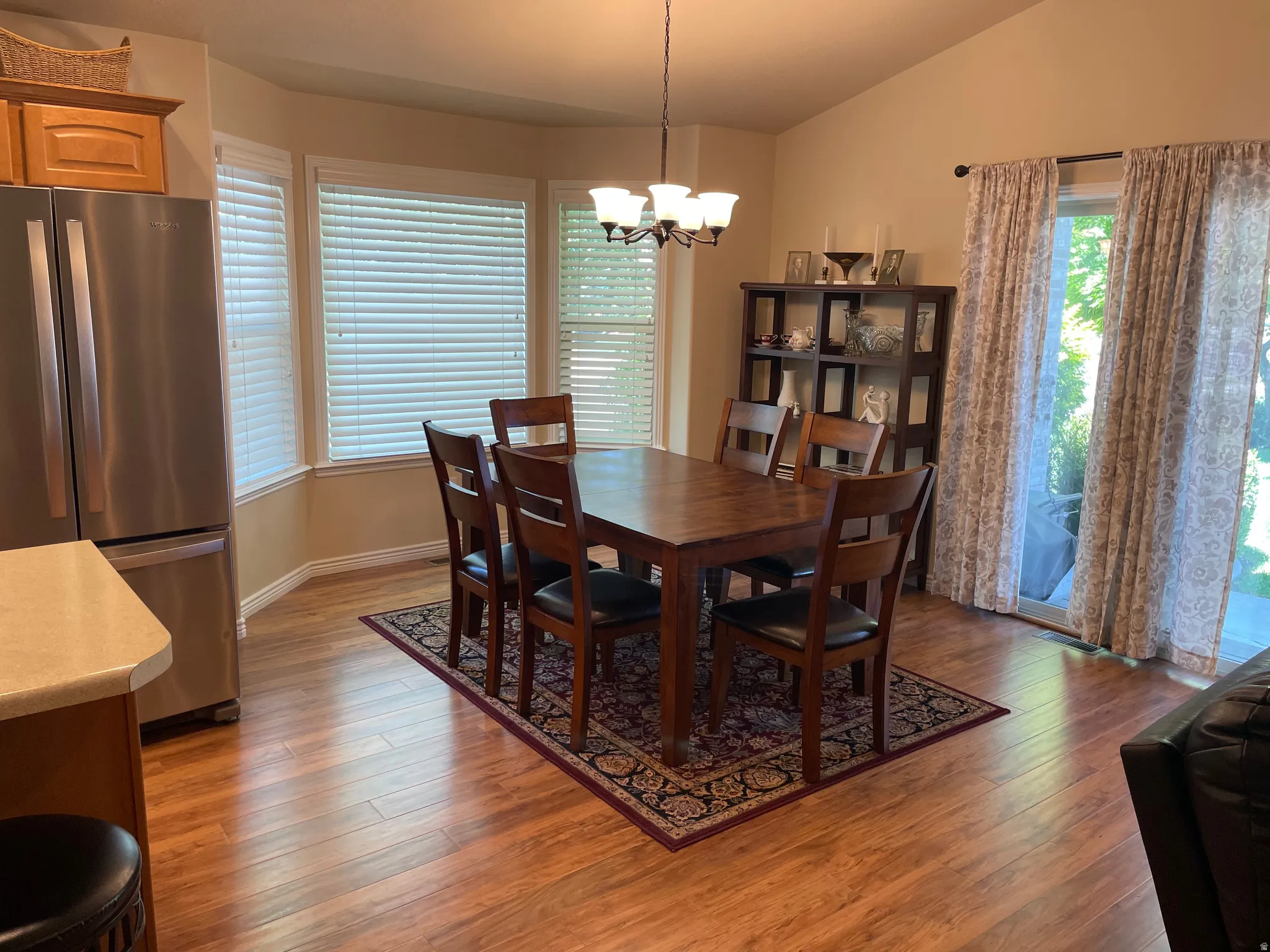 Dining area featuring wood-finish flooring, a bay window with blinds, and a sliding glass door