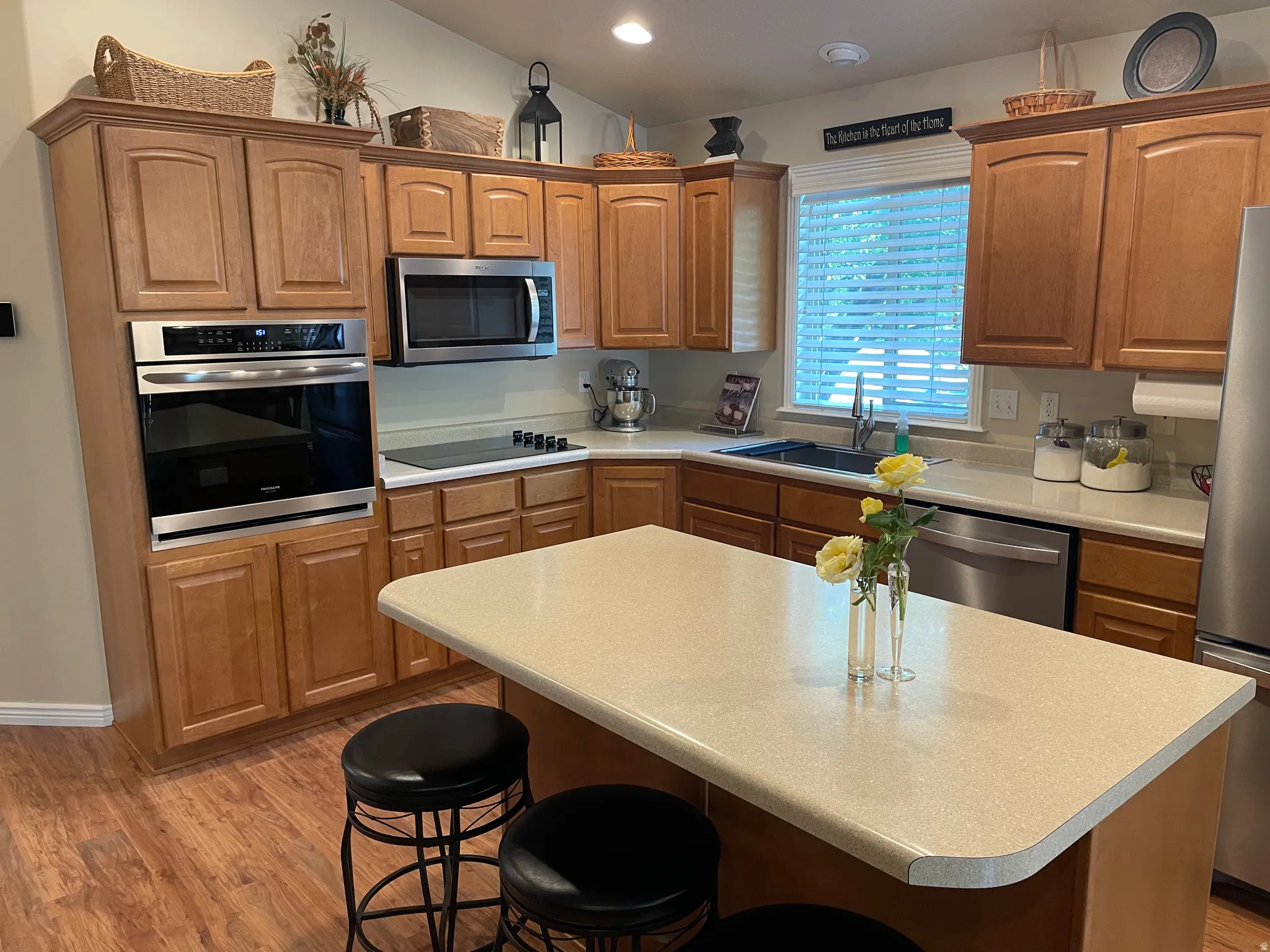 Kitchen with wood-finish flooring, light wood cabinetry, and stainless steel appliances