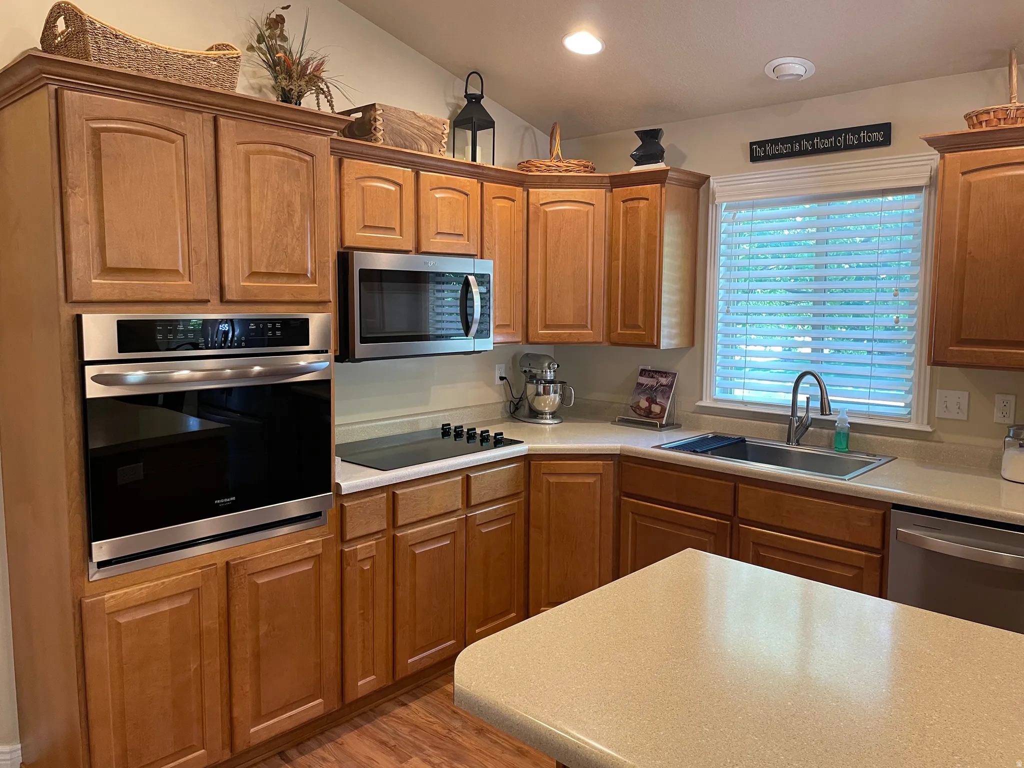 Contemporary kitchen featuring wood-finish cabinetry, stainless steel appliances including a wall oven and microwave, a smooth-top electric cooktop, and a double basin stainless steel sink