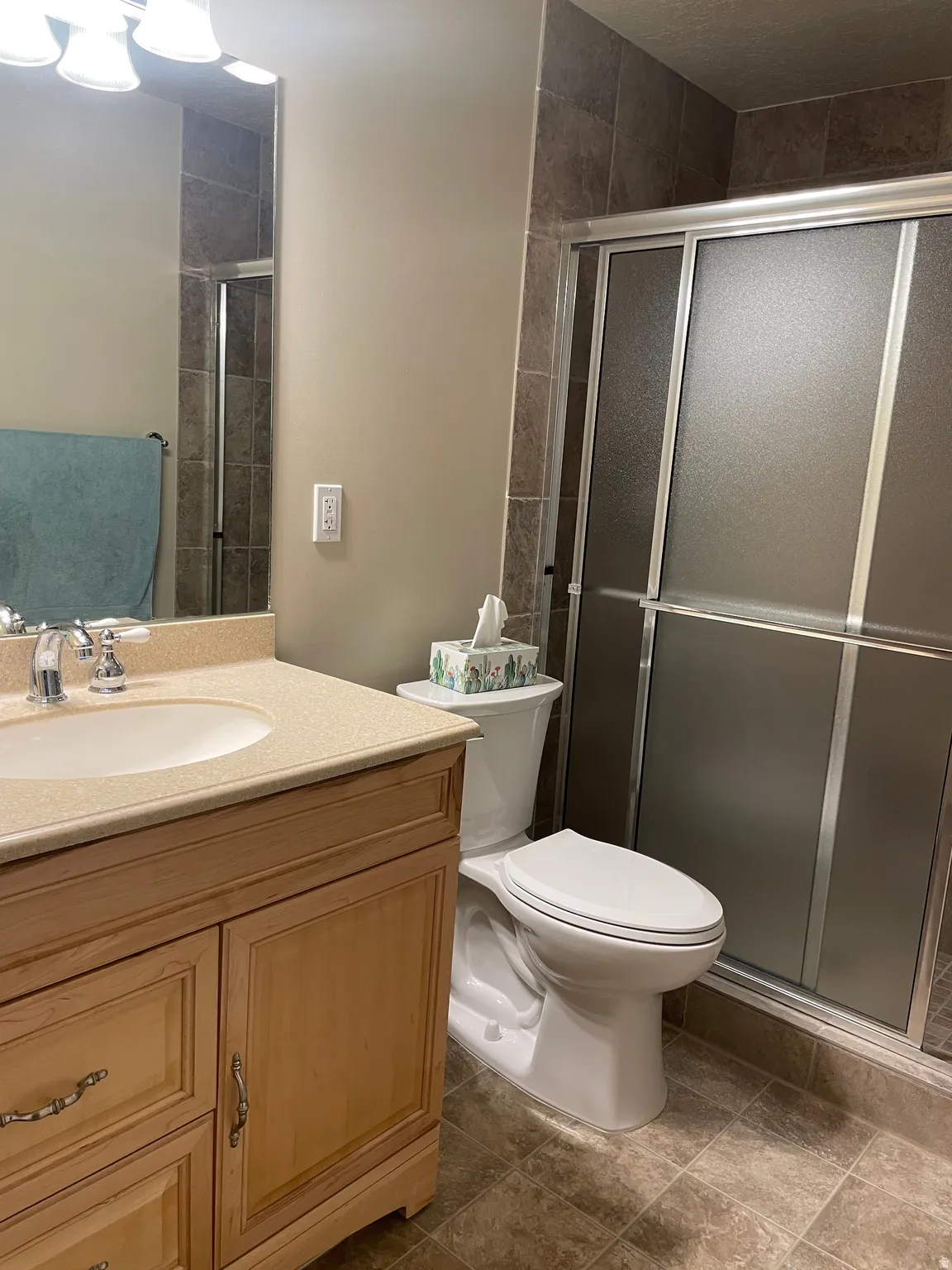 Bathroom featuring a single vanity with light wood cabinetry, a built-in sink, and a light-toned countertop
