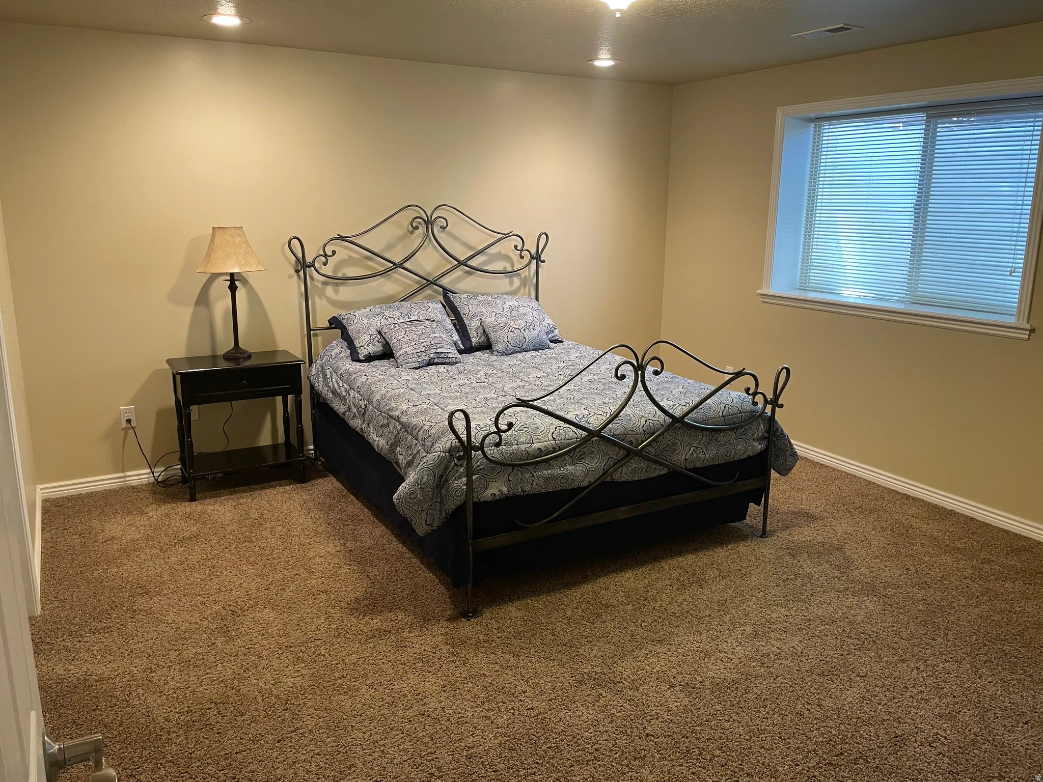 Carpeted room with recessed lighting and a window featuring horizontal blinds