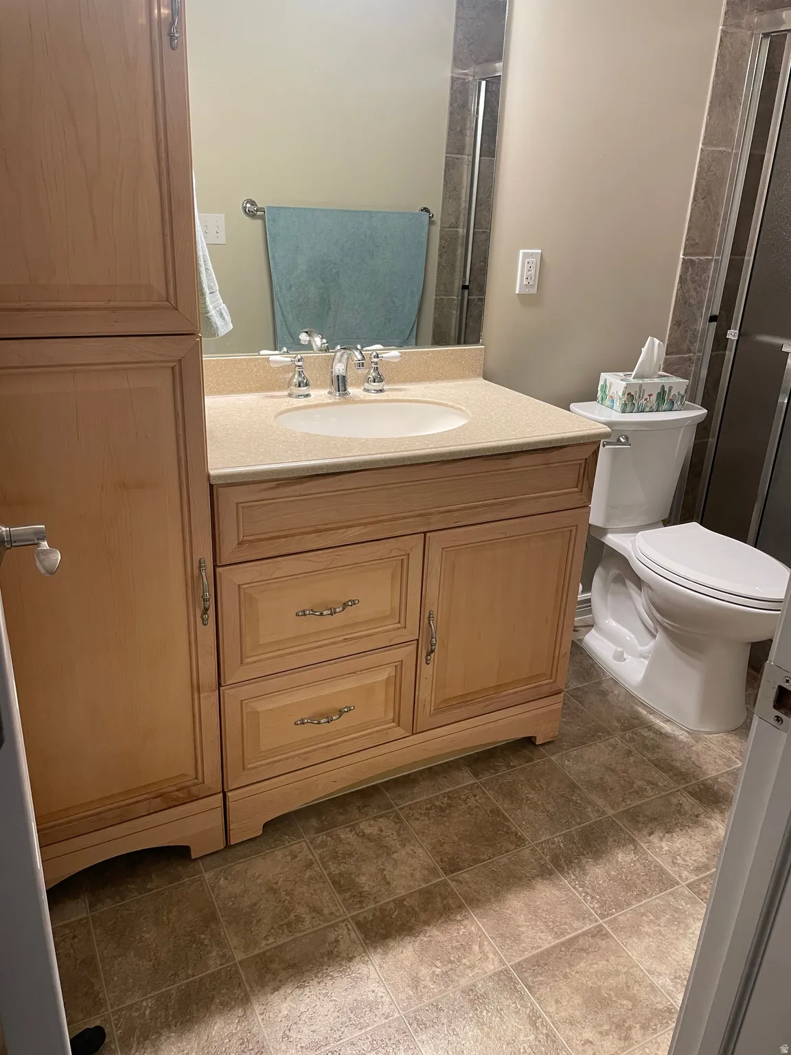 Bathroom vanity with light-toned cabinetry, an integrated sink, and a speckled countertop