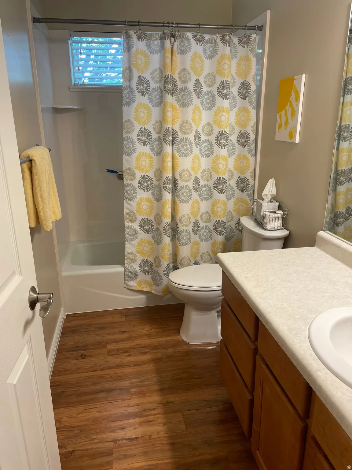 Bathroom featuring a white tub and shower combination, wood-finish flooring, and a vanity with a white countertop and integrated sink