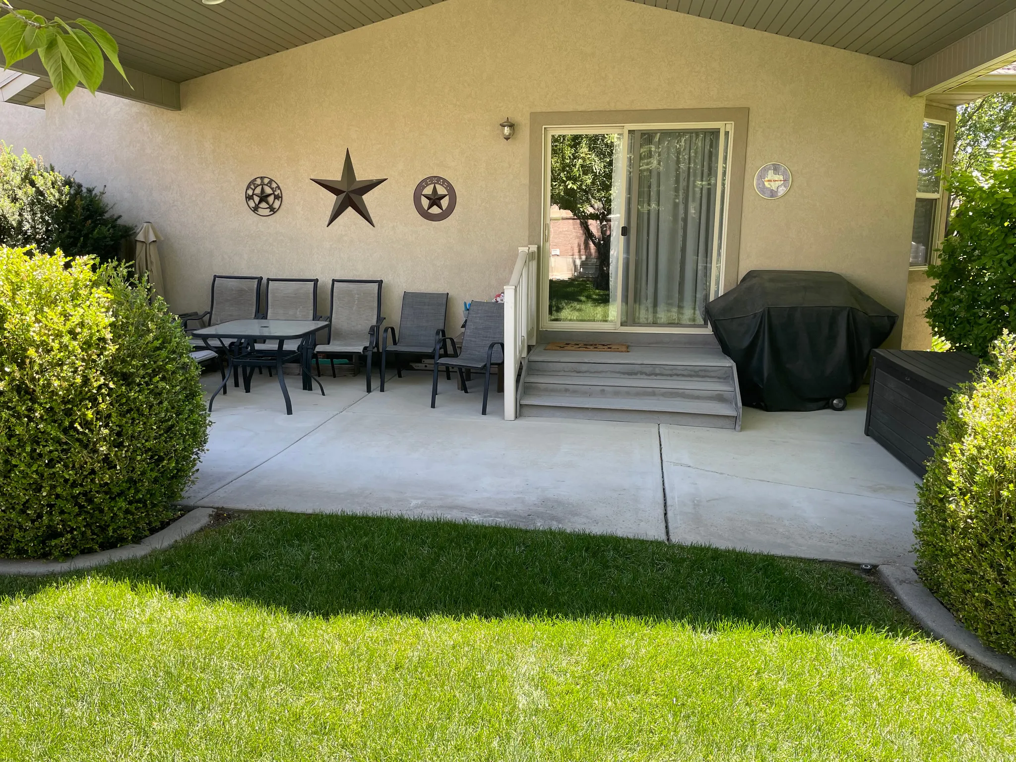 Covered concrete patio with stucco exterior, a sliding glass door, and wooden steps