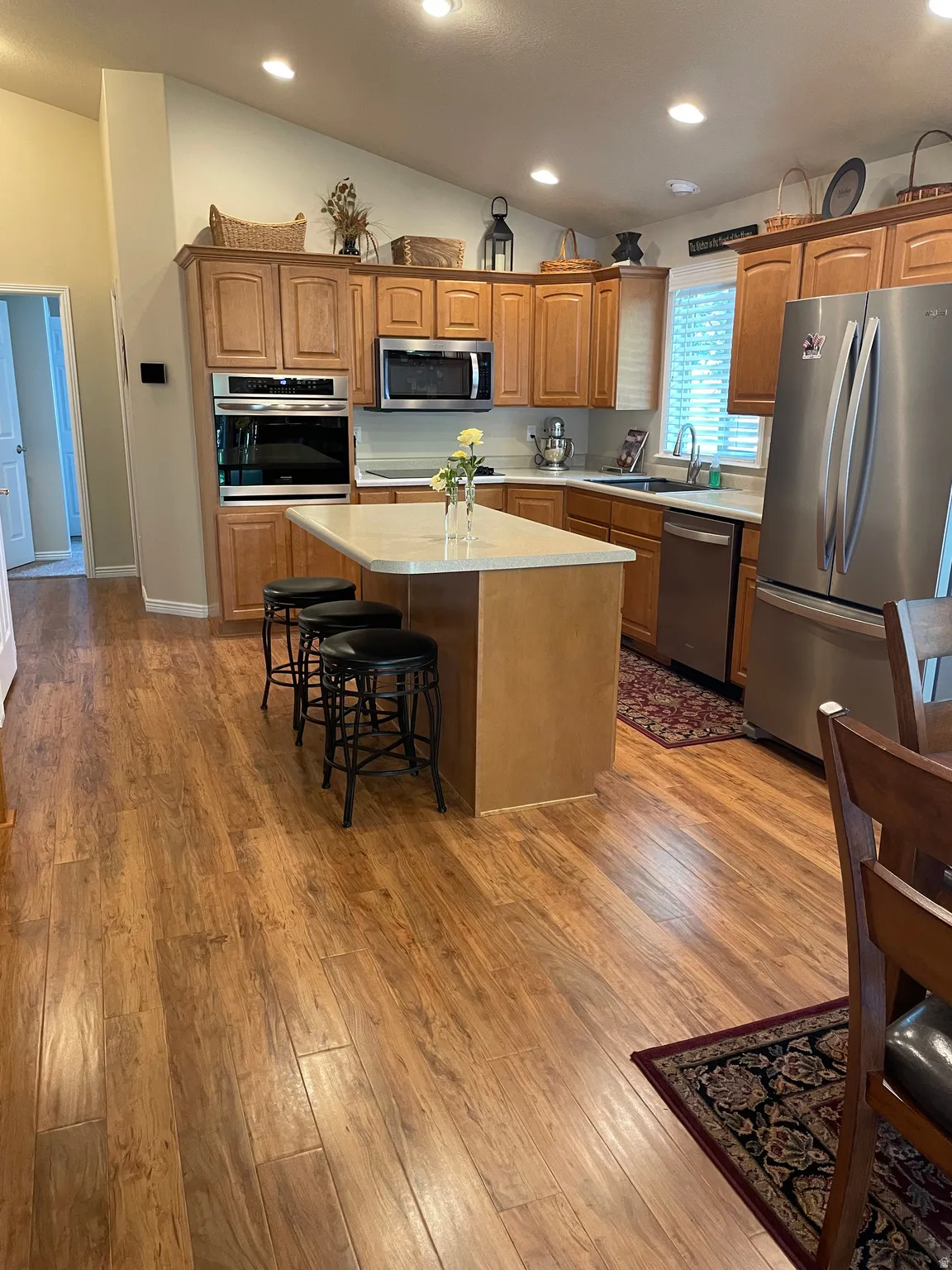 Kitchen featuring wood-finish flooring, light wood cabinetry, and stainless steel appliances