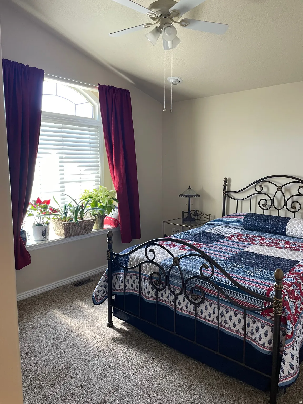 Bedroom featuring an arched window, white blinds, and a built-in ceiling fan with integrated lighting