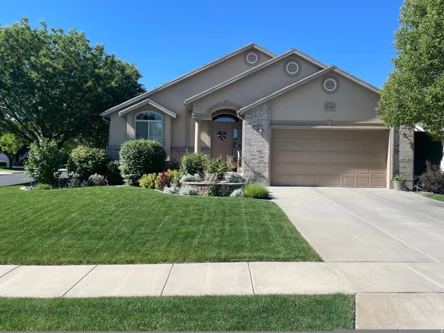 Stucco and stone facade with arched entry, complementing garage door, front landscaping, and a concrete driveway