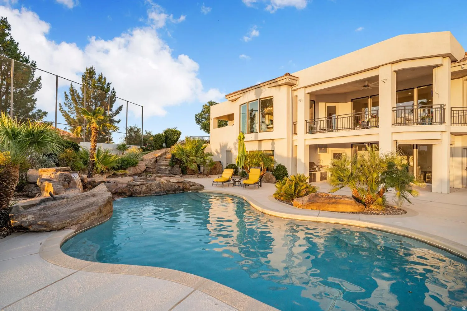 Resort-style pool with rock features and a waterfall, complemented by extensive hardscaping