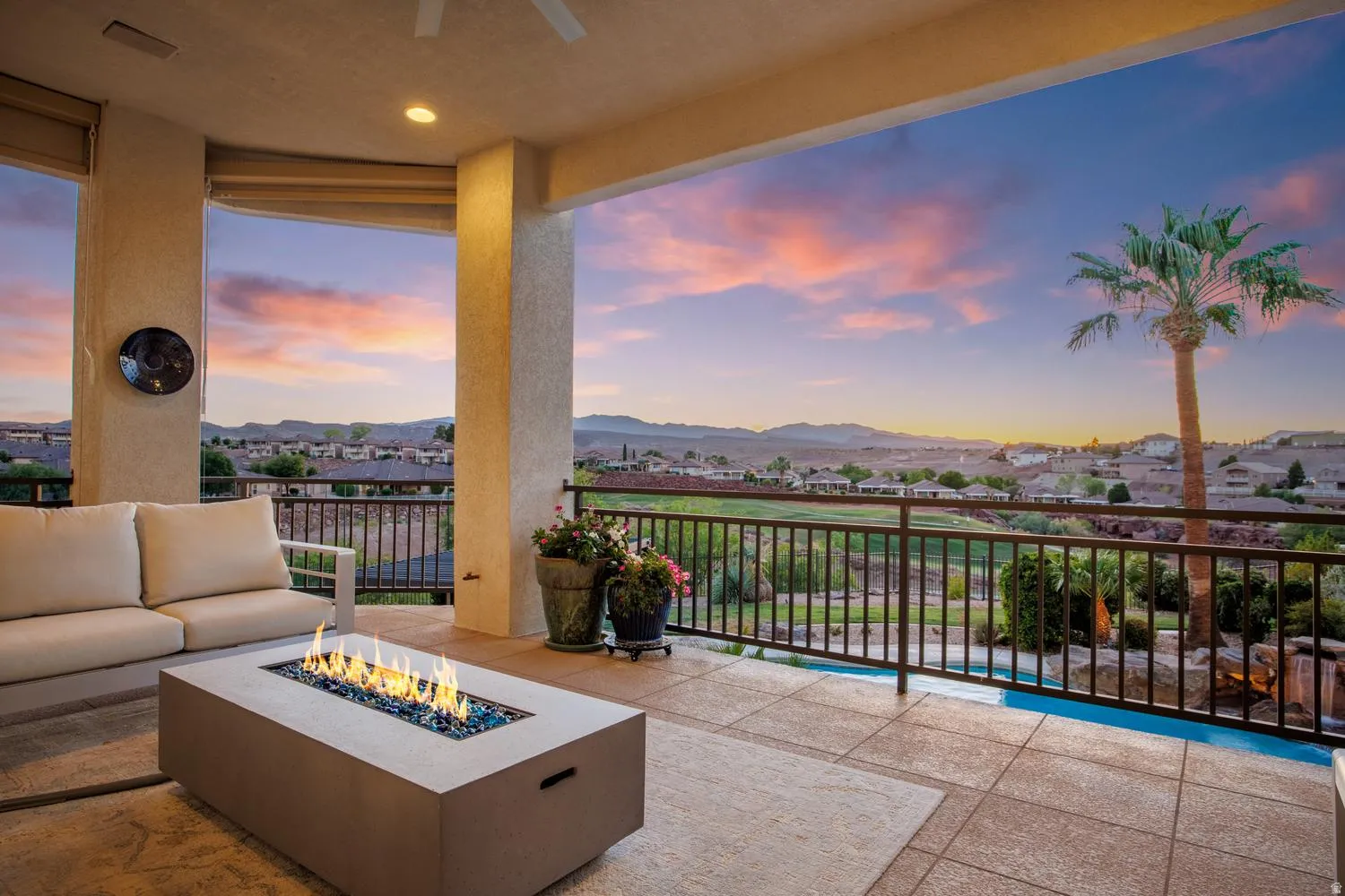 Covered patio featuring an outdoor fire pit with blue fire glass, ceiling fan, and recessed lighting