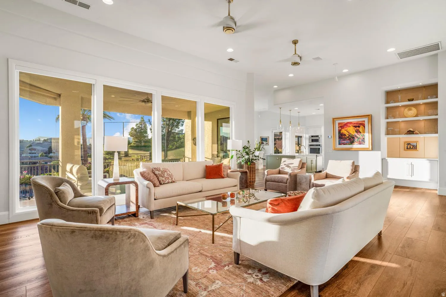 Spacious living area featuring large sliding glass doors, light wood-finish flooring, recessed lighting, and built-in shelving with glass fronts