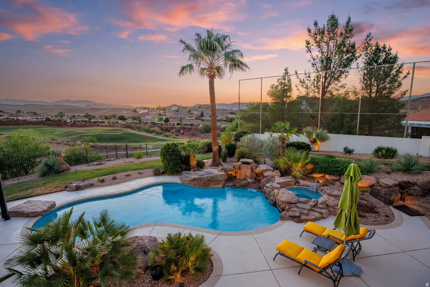 Resort-style pool area featuring a freeform swimming pool, rock waterfall, and integrated spa