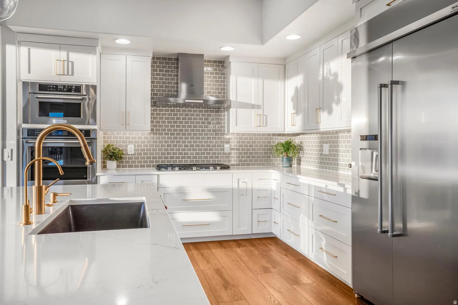 Kitchen featuring white cabinetry, light-toned countertop, stainless steel appliances, and wood-finish flooring