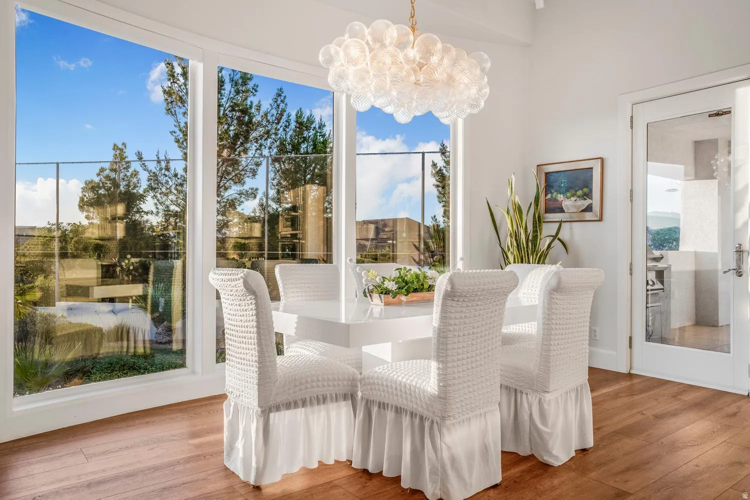 Dining area with expansive window wall, wood-finish flooring, a contemporary bubble chandelier, and a glass-paned door