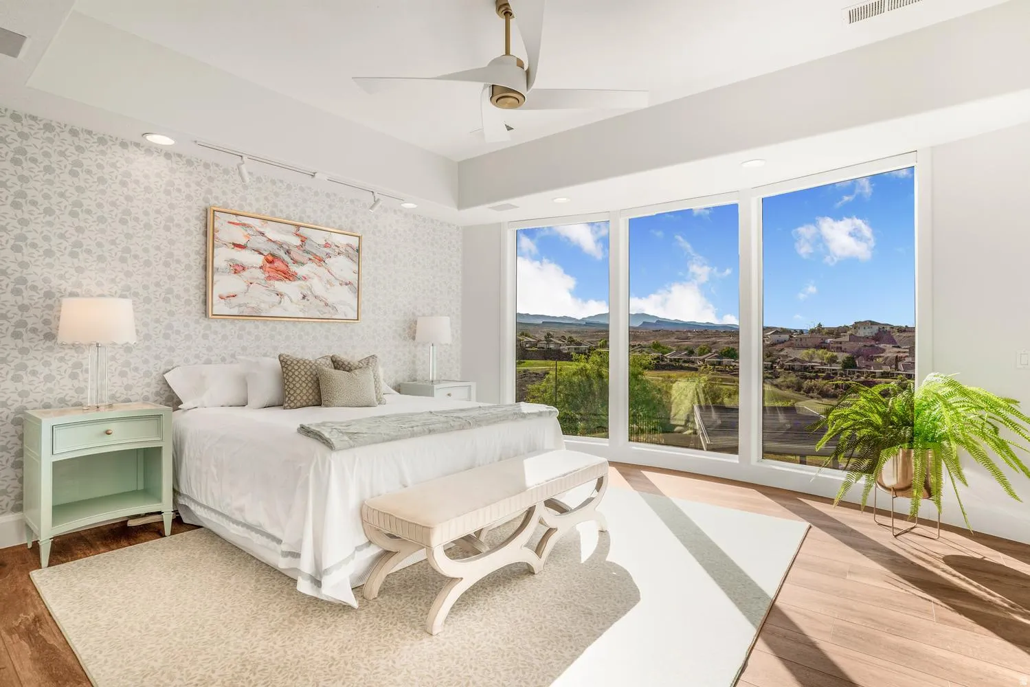 Floor-to-ceiling windows with expansive scenery, a tray ceiling with a modern ceiling fan, wood-finish flooring, recessed lighting, and patterned wall covering