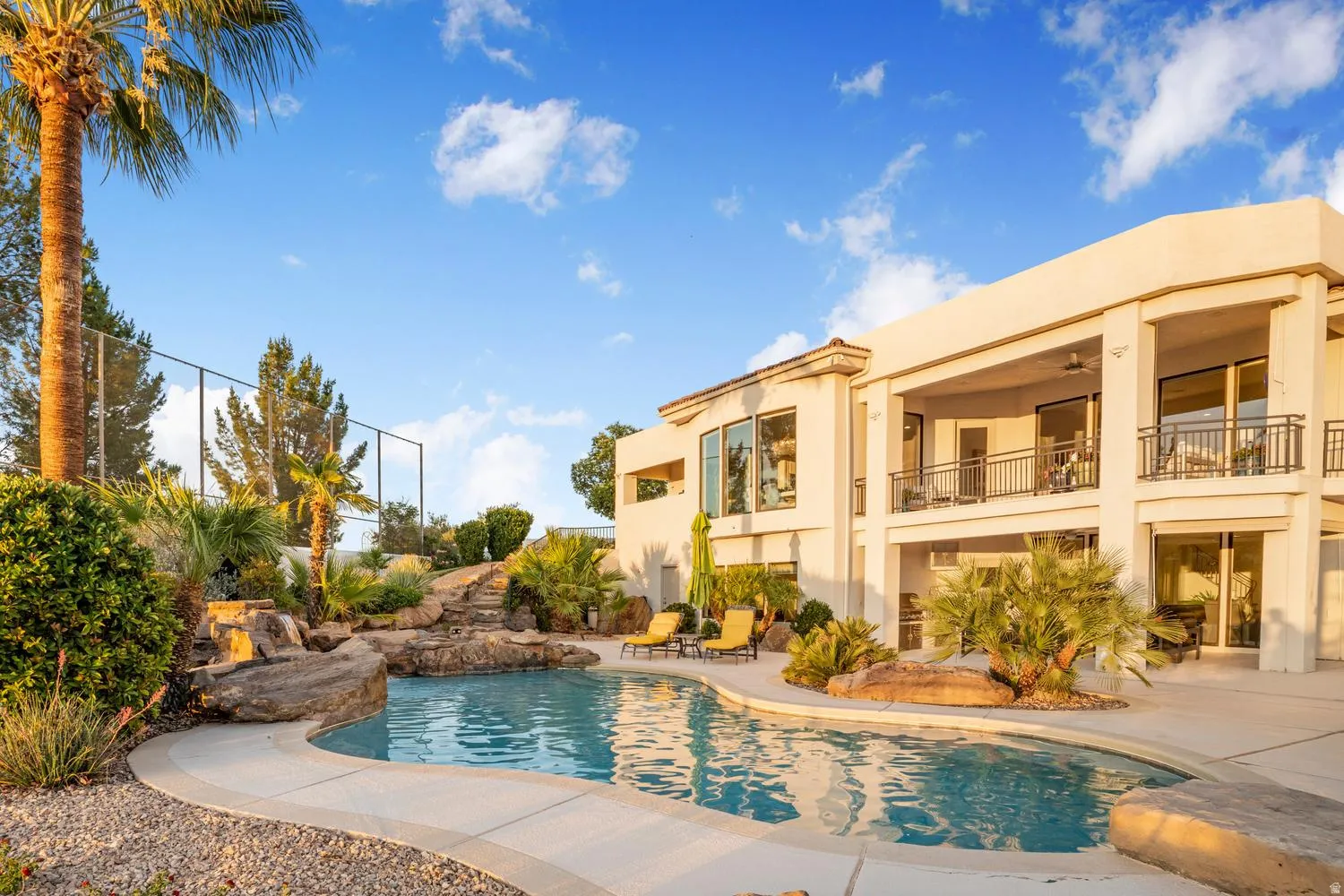 Custom-shaped swimming pool featuring a rock waterfall and integrated spa