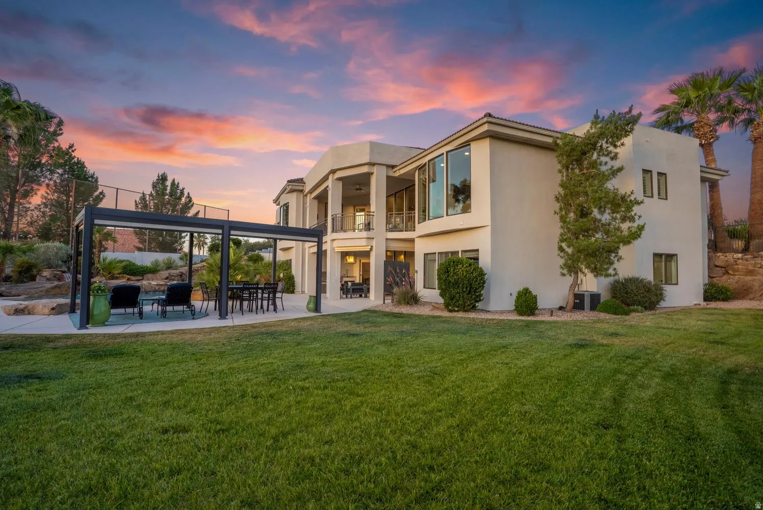 Expansive green lawn bordering a patio featuring a modern pergola structure