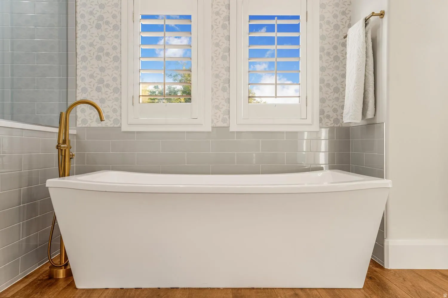 Freestanding white bathtub with a brass floor-mounted faucet