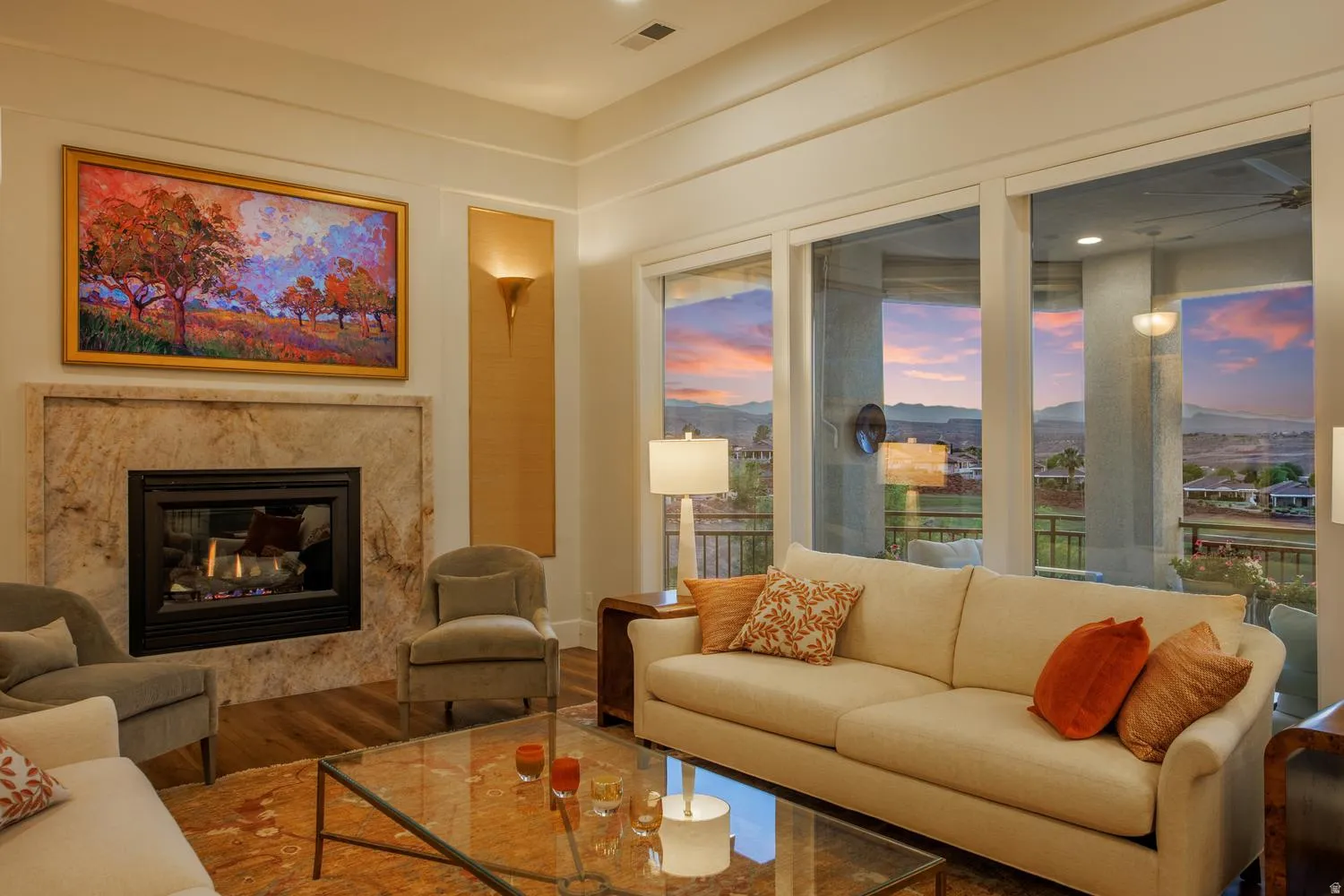 Living area featuring large format glass doors, a stone-surround fireplace, wood-finish flooring, and recessed ceiling lighting