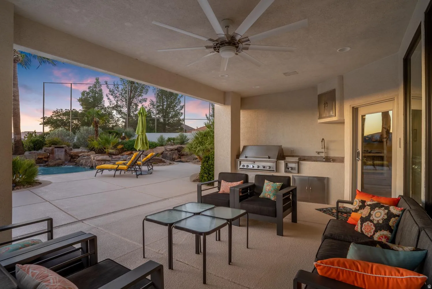 Covered patio with integrated outdoor kitchen, ceiling fan, built-in grill, and sink with stainless steel cabinetry