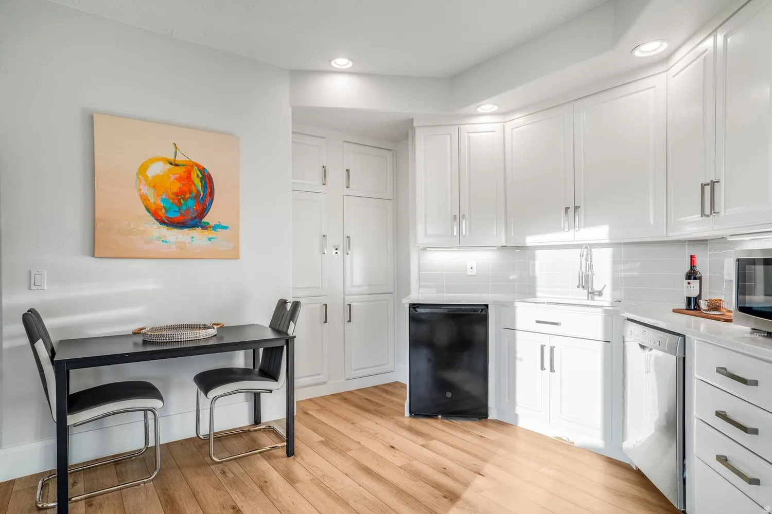Kitchen featuring white cabinetry, wood-finish flooring, recessed lighting, and a subway tile backsplash