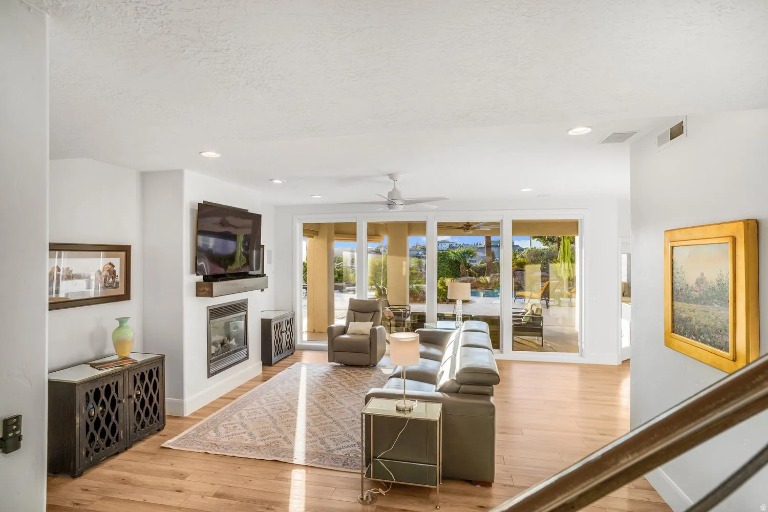 Spacious living area featuring wood-finish flooring, recessed lighting, and a contemporary fireplace
