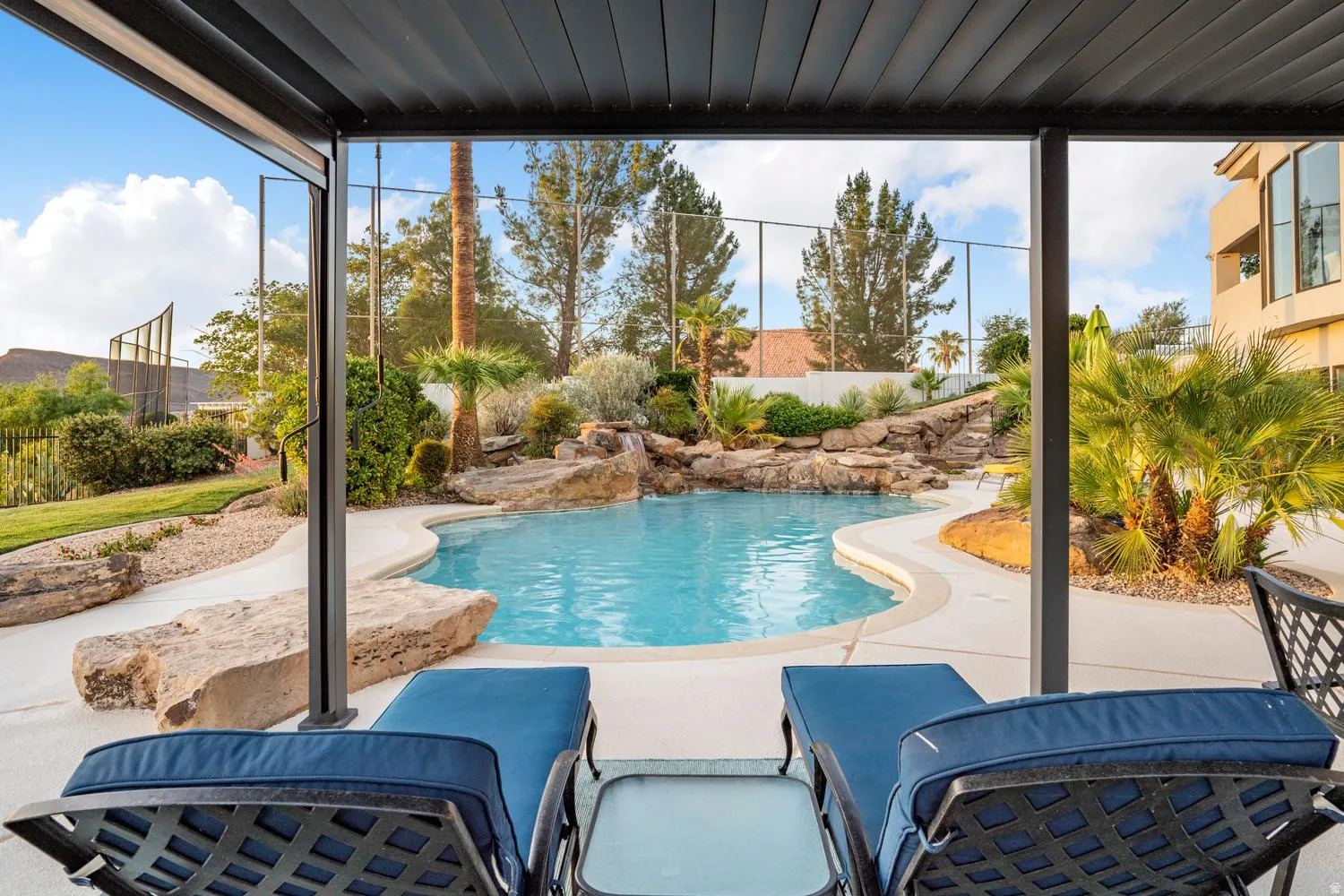 Covered patio overlooking a freeform swimming pool with a rock waterfall feature