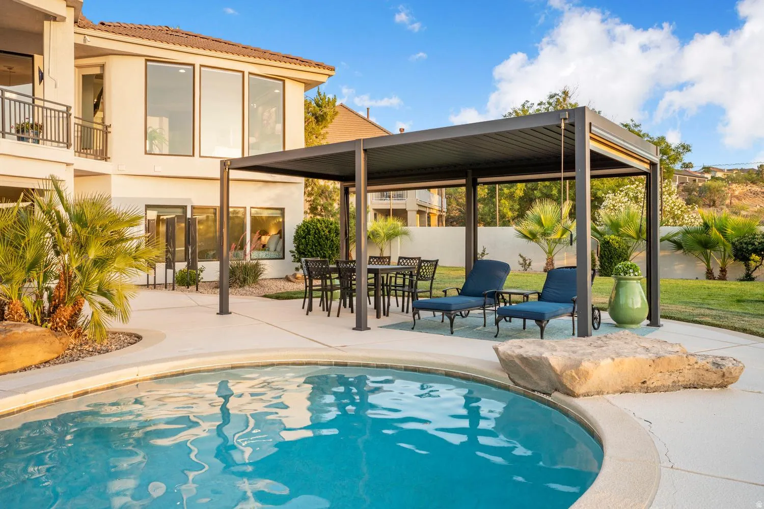 Outdoor swimming pool with integrated rock feature, surrounded by a concrete patio