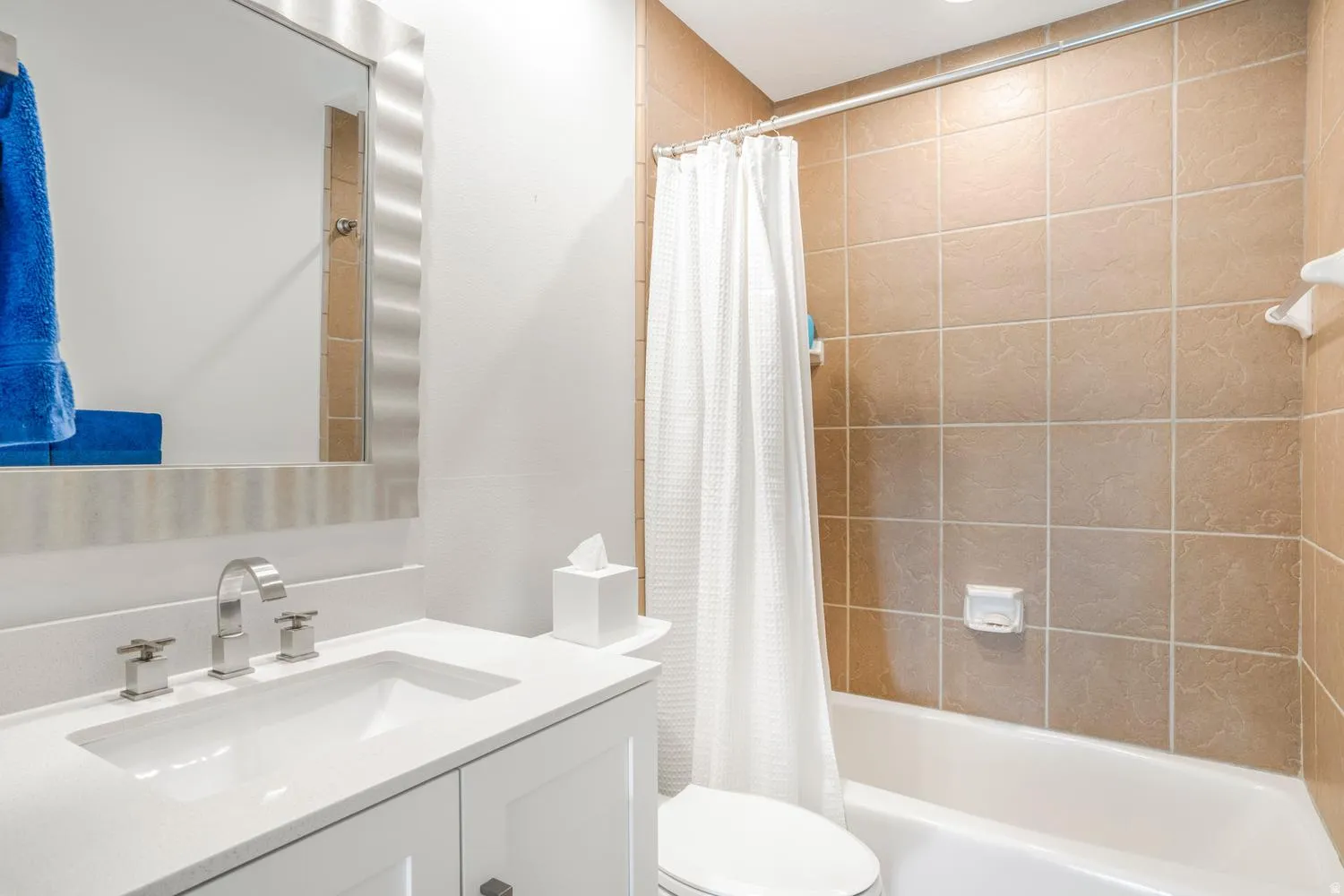 Bathroom featuring a white vanity with a rectangular undermount sink, a polished chrome faucet, and a large mirror with a brushed metal frame