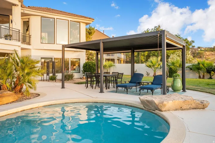 Outdoor swimming pool with integrated rock feature, surrounded by a concrete patio