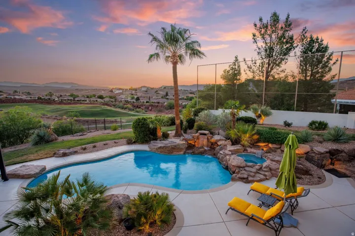 Resort-style pool area featuring a freeform swimming pool, rock waterfall, and integrated spa