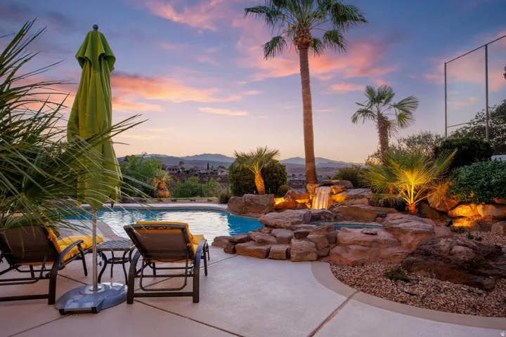 Resort-style backyard featuring a custom rock waterfall, integrated spa, and illuminated landscaping