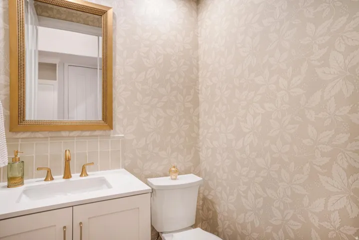 Bathroom featuring a vanity with a white countertop, gold-finish faucet, and a gold-framed mirror