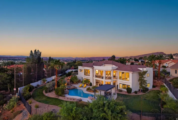 Multi-level residence featuring extensive rear landscaping, a large built-in swimming pool, a covered outdoor living area, and multiple upper-level balconies