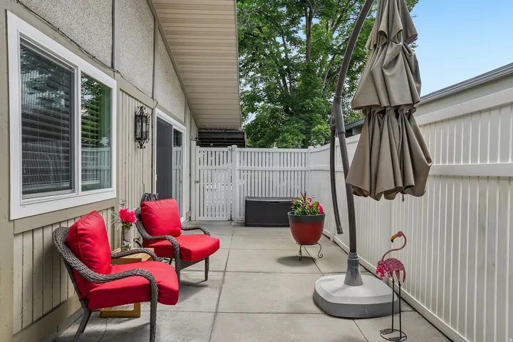 Paved patio area featuring a sliding glass door, white framed window, and vertical privacy fencing