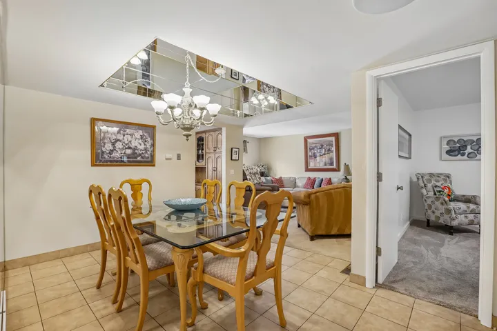 Dining space featuring tile flooring, a mirrored ceiling insert, and a classic chandelier