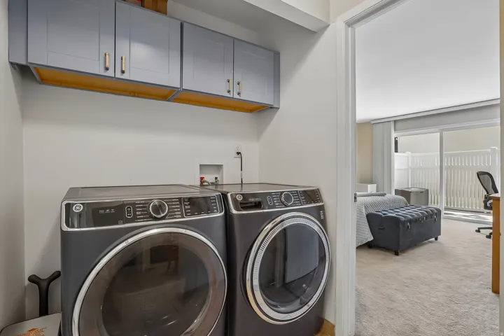 Dedicated laundry area featuring overhead cabinetry with gold-toned hardware