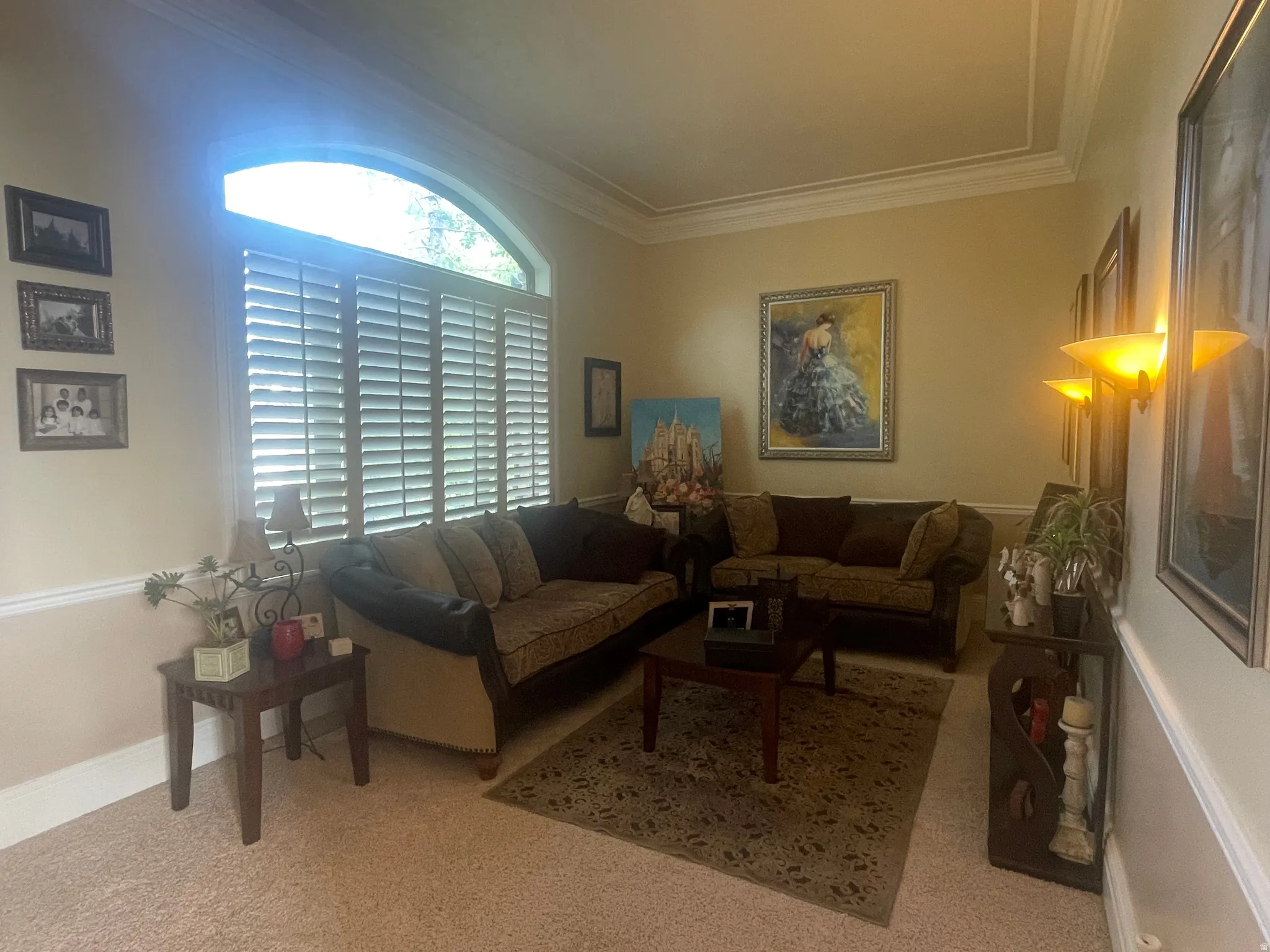 Room featuring an arched window with plantation shutters, crown molding, and chair rail detailing