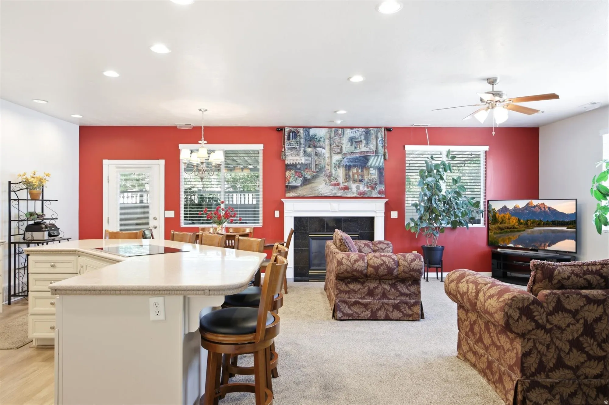 Open-concept living space featuring a U-shaped kitchen island with integrated cooktop, a white mantle fireplace, and recessed ceiling lighting