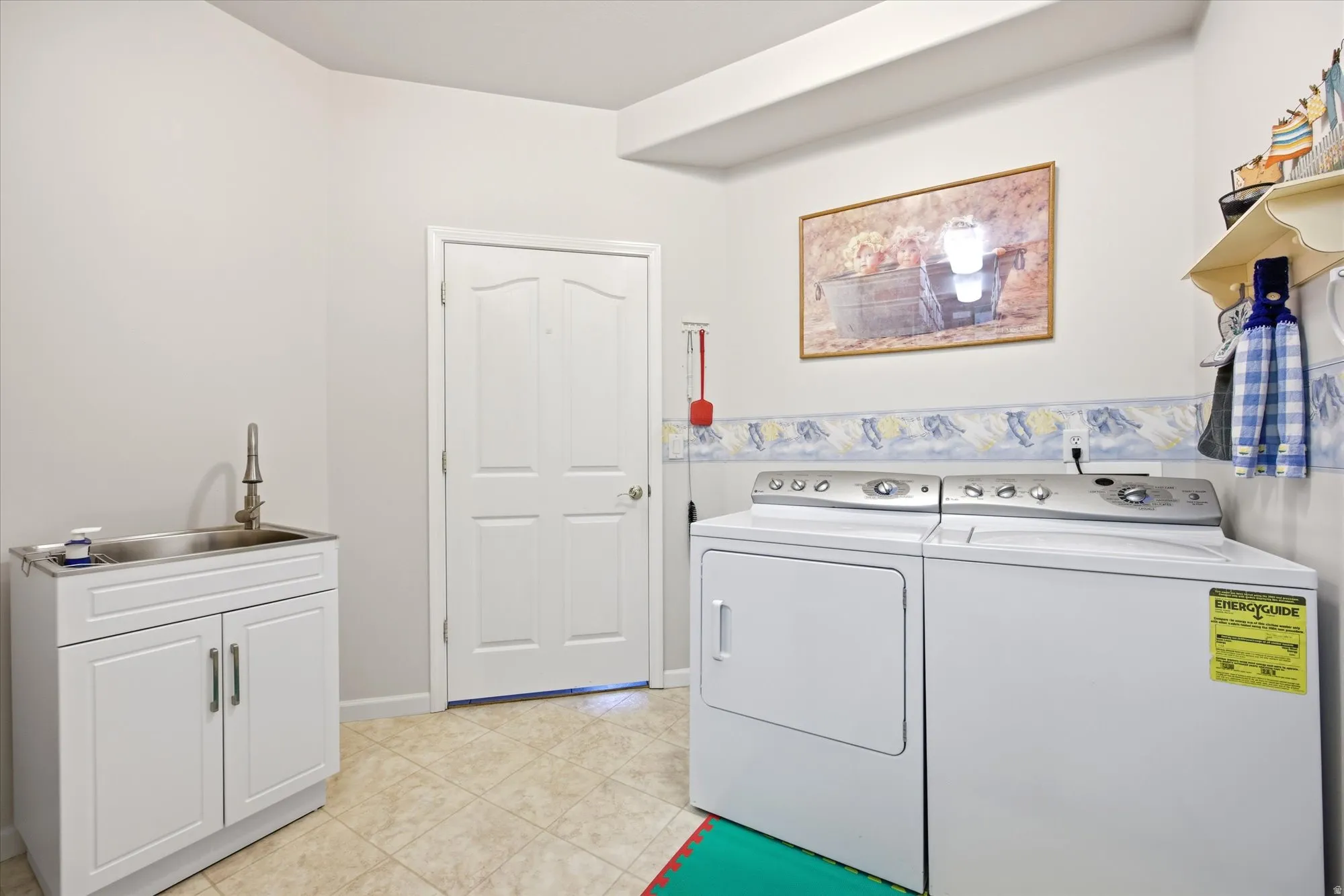 Dedicated utility room featuring light-toned walls, a white paneled door, and neutral tile flooring