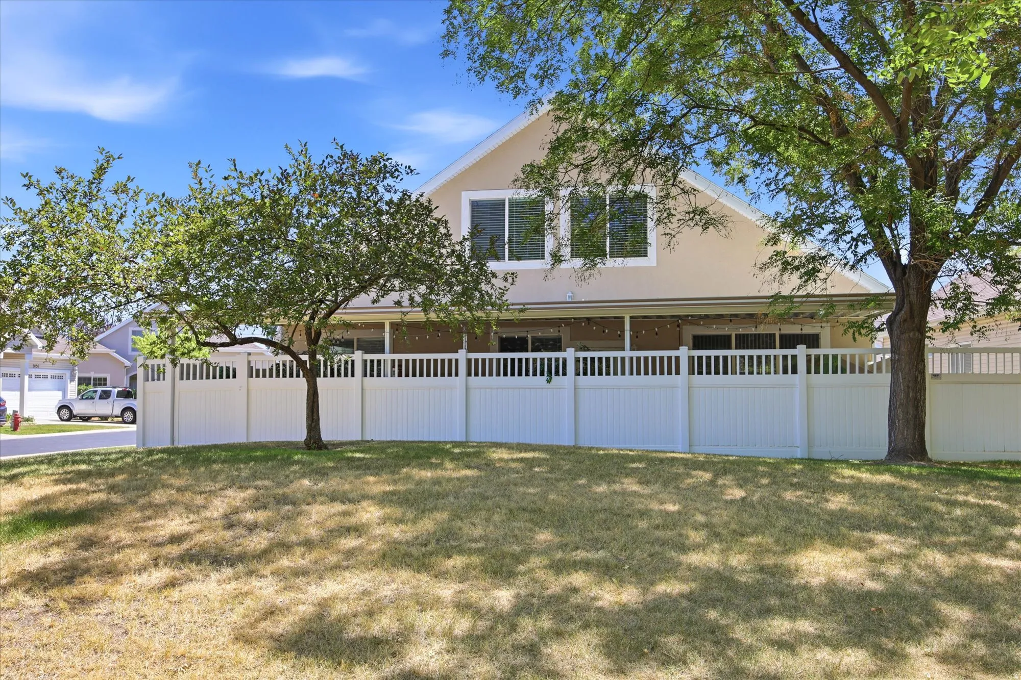 Rear exterior featuring a covered patio, upper-level windows, and a white picket-style fence